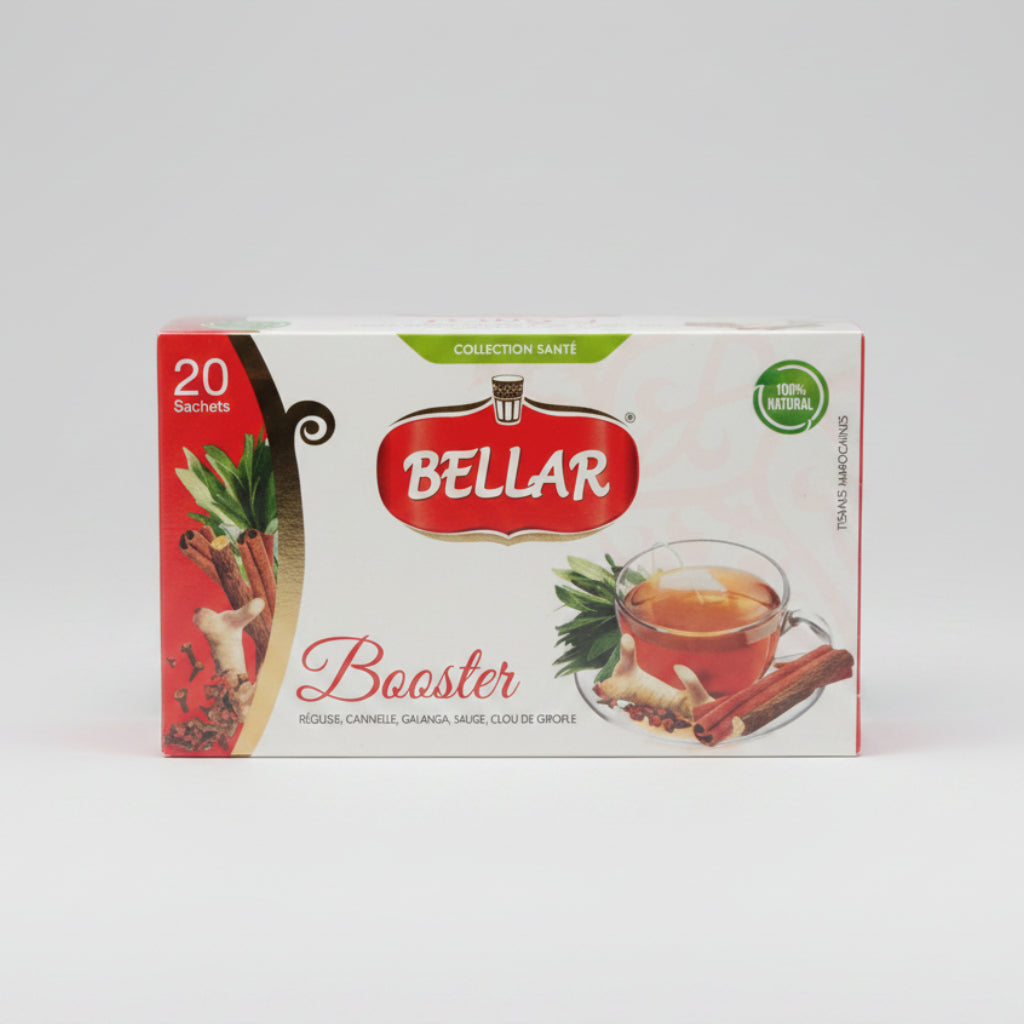 A box of Bellar Booster tea sachets, featuring red and white packaging with illustrations of ginger and a cup of tea, placed on a dark reflective surface with a blurred kitchen background.